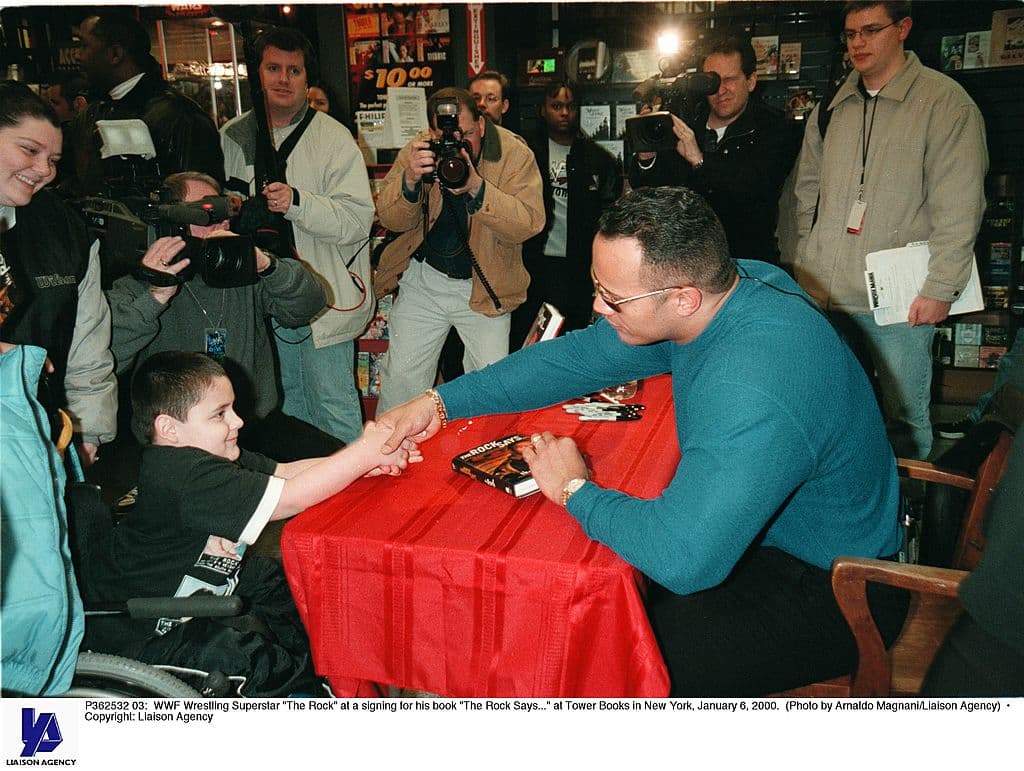 La superestrella de la WWF saluda a un niño en silla de ruedas en la firma de autógrafos de su libro "The Rock Says ..." en Tower Books en Nueva York, 6 de enero de 2000.