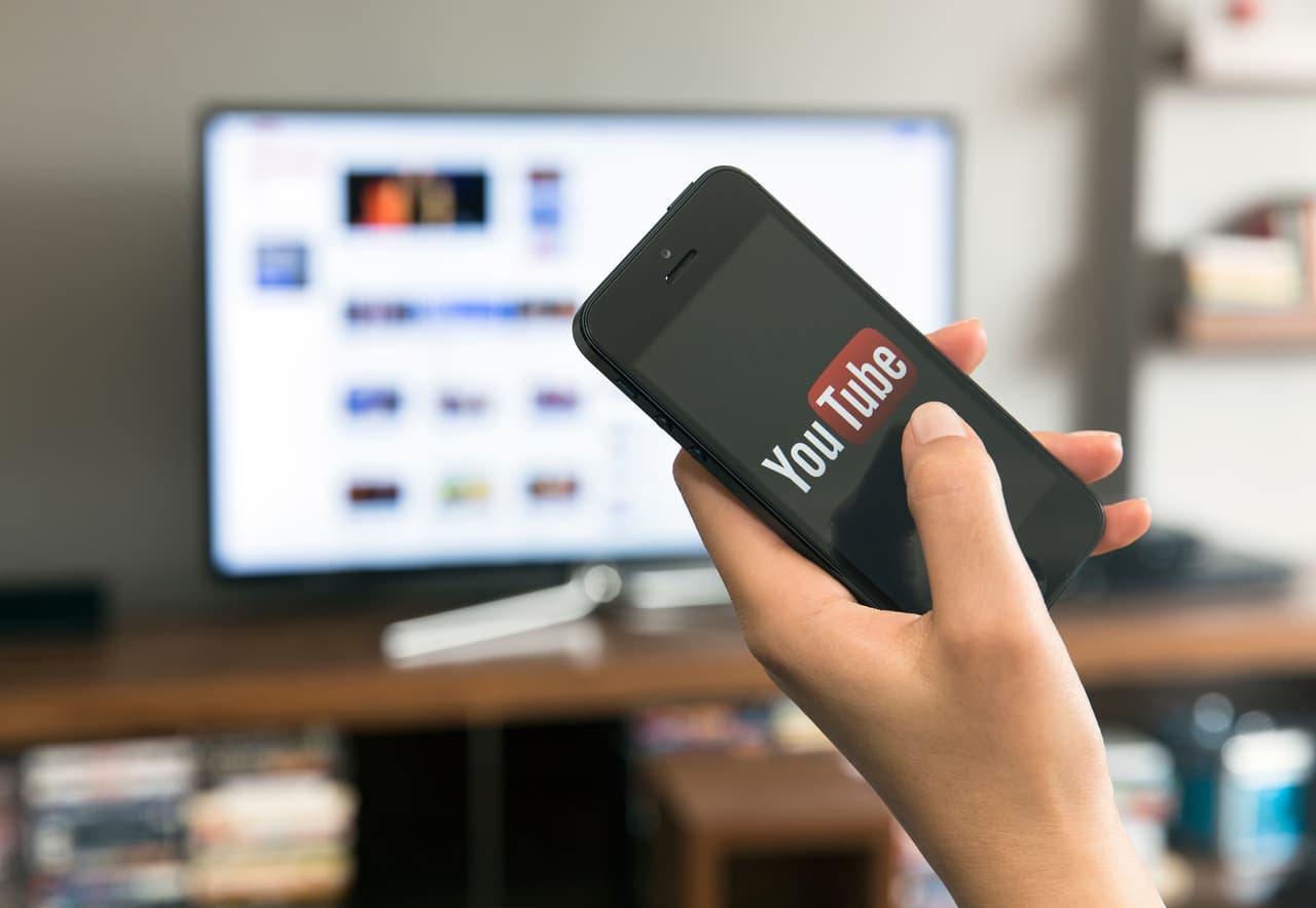 "istanbul, Turkey - March 14, 2013: Watching YouTube videos on smart tv with home media sharing technology. Woman hand holding and touching Apple iPhone 5. iPhone 5 displaying log in screen of YouTube application. The iPhone 5 is smartphone with multi touch screen produced by Apple Computer, Inc. YouTube is one of the most popular video sharing sites."