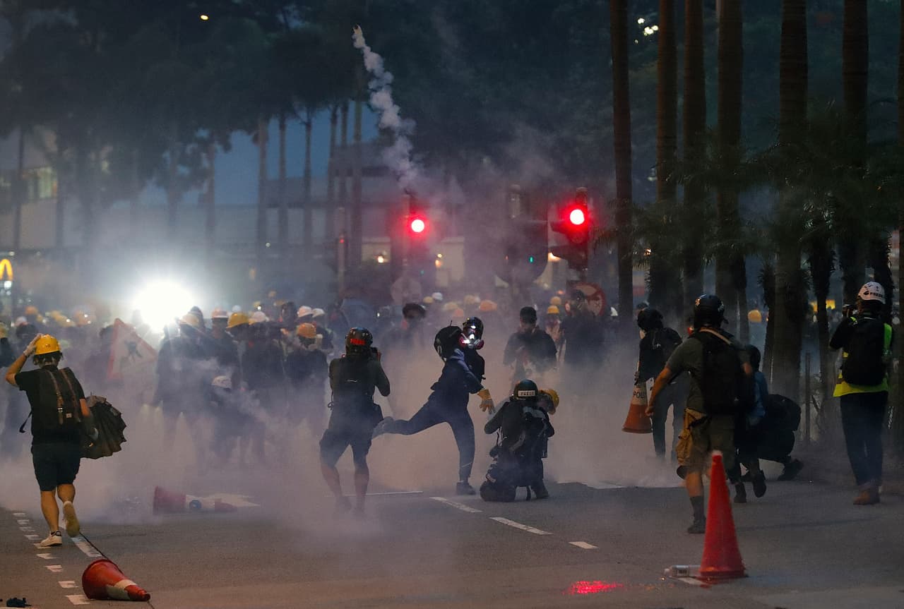 A protester throws a tear gas canister fired by riot policemen during the anti-extradition bill protest in Hong Kong, Sunday, Aug. 11, 2019. Police fired tear gas late Sunday afternoon to try to disperse a demonstration in Hong Kong as protesters took over streets in two parts of the Asian financial capital, blocking traffic and setting up another night of likely showdowns with riot police. (AP Photo/Vincent Thian)